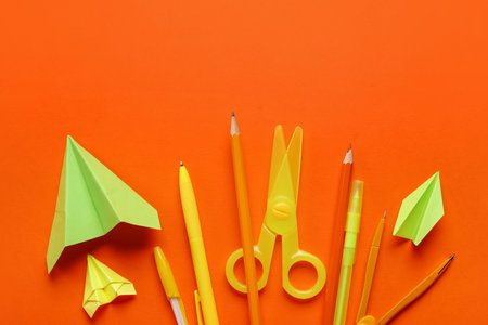 Composition with stationery supplies and paper plane on orange backgroundの写真素材