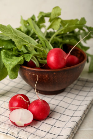 Bowl of ripe radish with green leaves on tableの写真素材