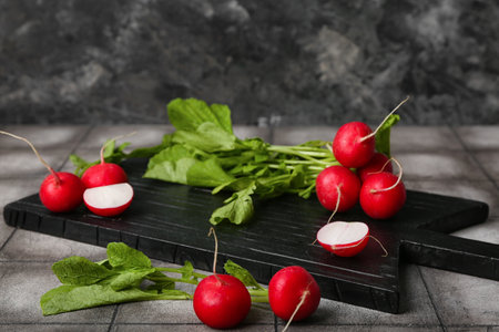 Wooden board of ripe radish with green leaves on tableの写真素材