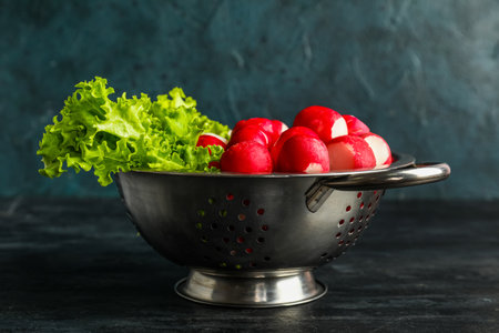 Colander with fresh radish on dark backgroundの写真素材