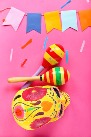 Mexican maracas with painted skull, paper flags and confetti on pink backgroundの写真素材