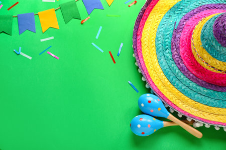 Frame made of Mexican maracas with sombrero hat, flags and confetti on green backgroundの写真素材
