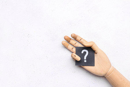 Wooden hand with paper question mark on white backgroundの写真素材