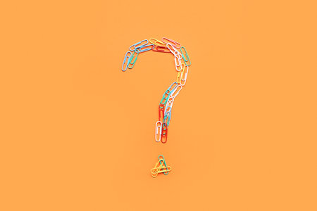 Question mark made of paper clips on orange backgroundの写真素材