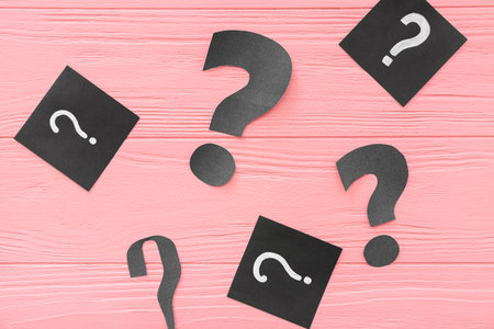 Paper question marks on pink wooden background