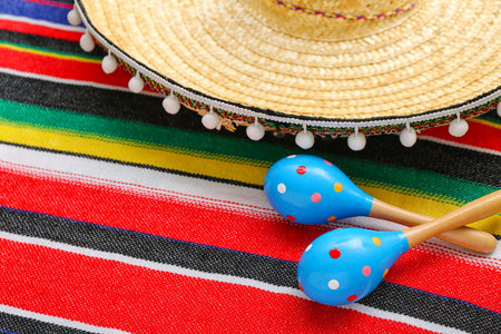 Mexican maracas with sombrero hat on colorful serape, closeup