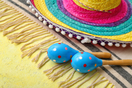 Mexican maracas with sombrero hat and serape on yellow background, closeup