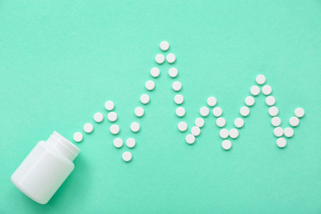 Bottle with cardiogram made of white pills on mint background