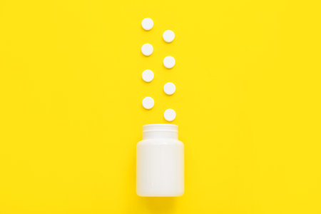 Bottle with white pills on yellow backgroundの写真素材