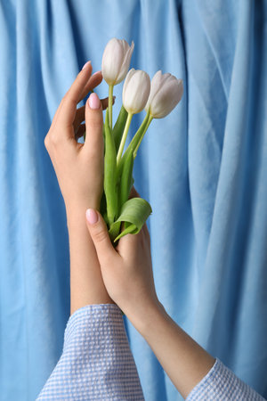 Woman with white tulips against blue fabric background. hand care conceptの写真素材