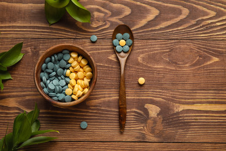 Bowl with pills, spoon and plant branches on wooden backgroundの写真素材