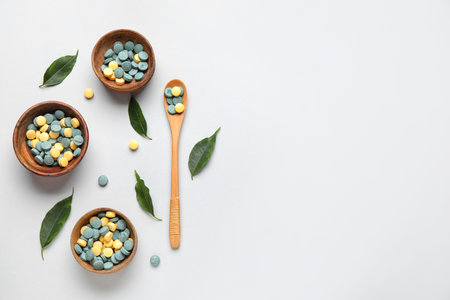 Bowls with pills, spoon and leaves on white backgroundの写真素材