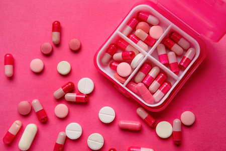 Container with pills on pink backgroundの写真素材