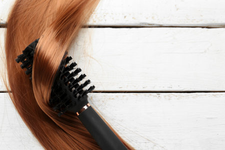 Round brush with hair strand on white wooden backgroundの写真素材