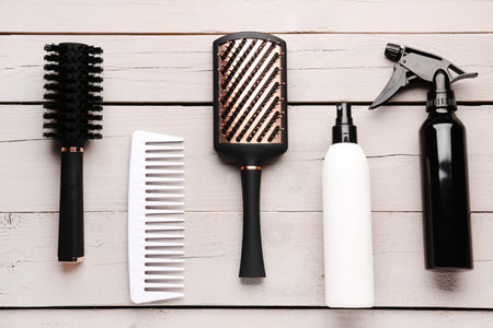 Hair brushes with spray bottles on light wooden backgroundの写真素材