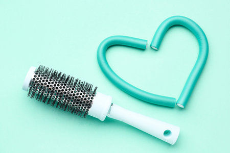Heart made of curlers with brush on mint backgroundの写真素材