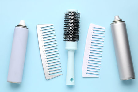 Hair brushes with spray bottles on blue background