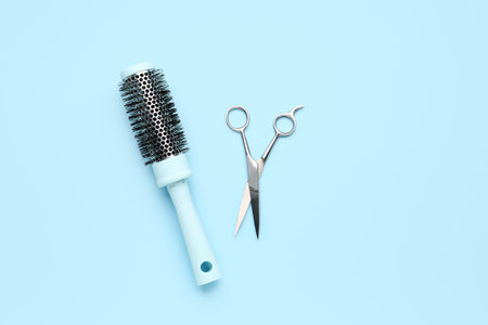 Round hair brush with scissors on blue background