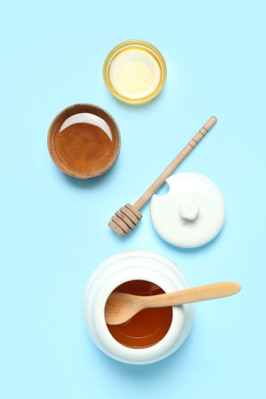 Bowls and jar with sweet honey on blue backgroundの写真素材