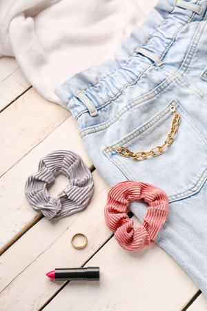 Silk scrunchies with jewelry, lipstick and jeans on white wooden background, closeupの写真素材