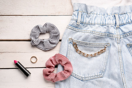 Silk scrunchies with jewelry, lipstick and jeans on white wooden background, closeupの写真素材