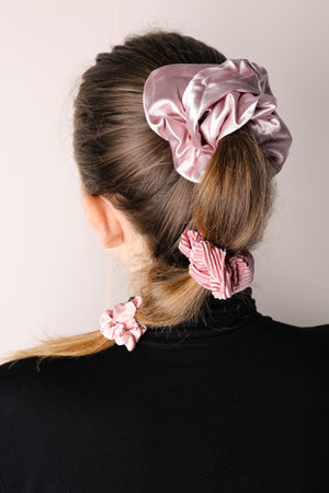 Woman with stylish hairdo and silk scrunchies on light background, back viewの写真素材