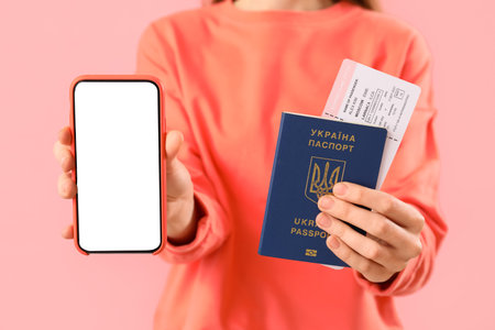Woman with Ukrainian passport, ticket and mobile phone on pink background, closeupの写真素材