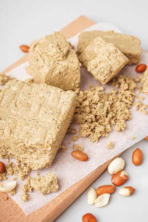 Wooden board of tasty halva with peanuts on light background, closeupの写真素材