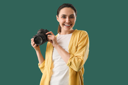Female photographer with professional camera on green backgroundの写真素材