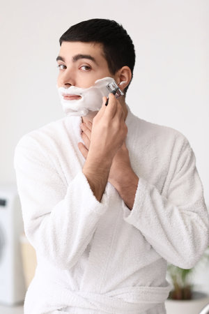 Young man shaving in the bathroomの写真素材