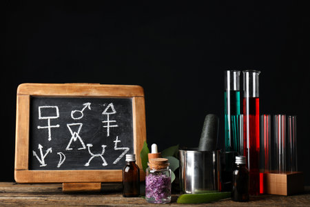 Potions and chalkboard with symbols on alchemist's tableの写真素材
