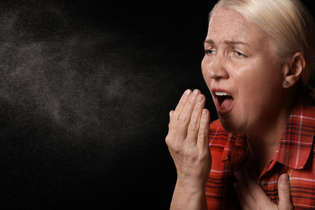 Coughing mature woman on dark background. concept of epidemicの写真素材