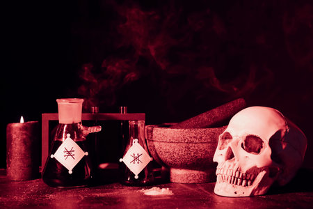Potions, human skull, mortar and pestle on alchemist's tableの写真素材