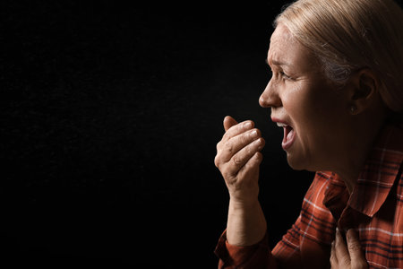 Coughing mature woman on dark background. concept of epidemicの写真素材