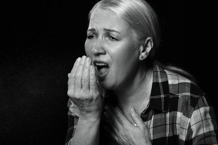 Coughing mature woman on dark background. concept of epidemicの写真素材