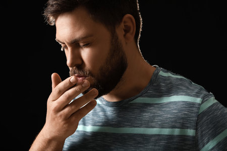 Coughing man on dark background. concept of epidemicの写真素材