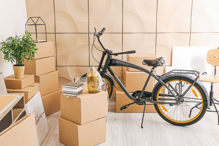 Cardboard boxes with accessories and bicycle in new flat on moving dayの写真素材