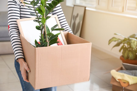 Woman with accessories in cardboard box on moving dayの写真素材
