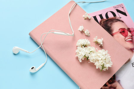 Composition with beautiful lilac flowers, earphones, notebook and fashion magazine on color backgroundの写真素材