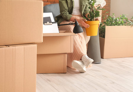 Woman with accessories in cardboard boxes on moving day