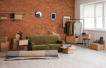 Cardboard boxes with accessories and sofa in new flat on moving dayの写真素材