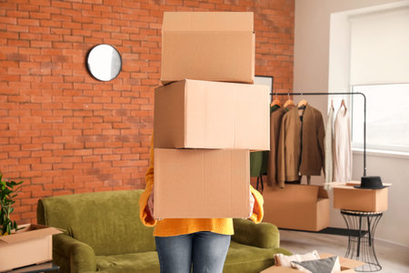 Woman with accessories in cardboard boxes on moving day