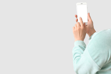 Woman with mobile phone on light backgroundの写真素材