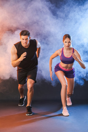 Sporty running young couple on dark backgroundの写真素材