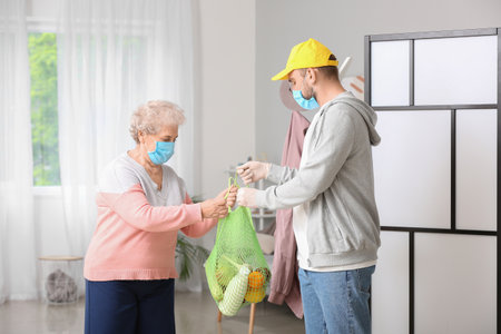 Senior woman receiving food from courier at home. concept of epidemicの写真素材