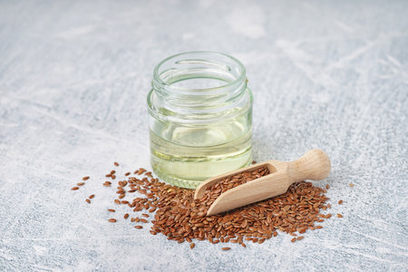 Jar with flax oil and seeds on light grunge backgroundの写真素材