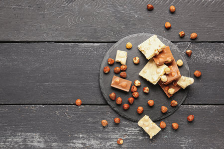 Different tasty chocolate with nuts on dark wooden backgroundの写真素材