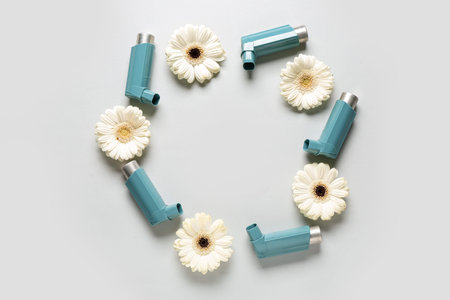 Frame made of inhaler with flowers on gray background