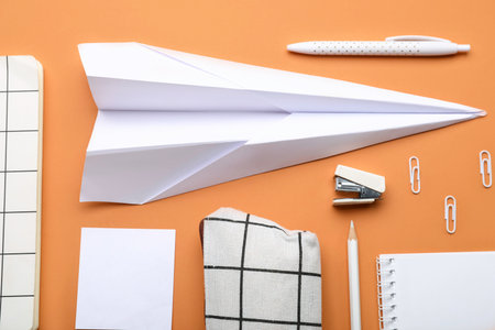 Composition with stationery supplies and paper plane on orange backgroundの写真素材