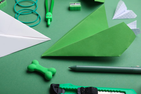 Composition with stationery supplies and paper planes on green backgroundの写真素材